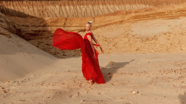 フルレングスのポートレート。砂漠で赤いドレスを着た若い女性ダンサーの写真。フルレングスのポートレート。