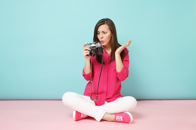 Full length portrait young woman in rose shirt blouse white pants sitting on floor hold camera 