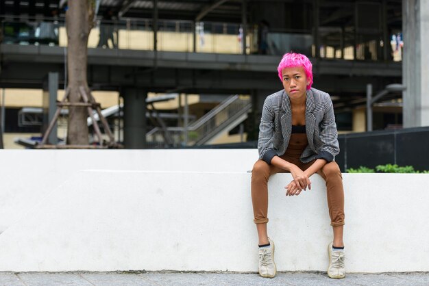 Full length portrait of young woman sitting outdoors