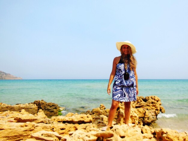 Full length portrait of young woman standing at beach