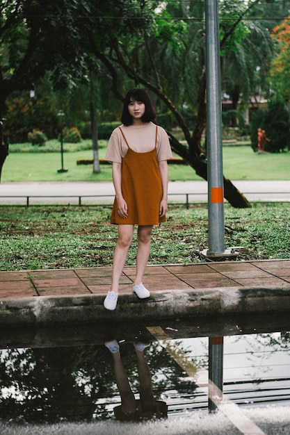 Photo full length portrait of young woman standing on sidewalk by puddle