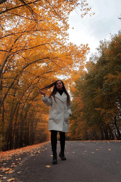 Foto ritratto a tutta lunghezza di una giovane donna che cammina nel parco durante l'autunno