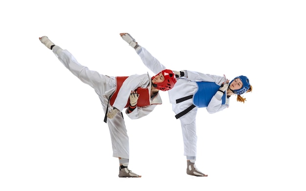 Full-length portret van twee professionele taekwondo feale atleten vechten geïsoleerd op witte achtergrond