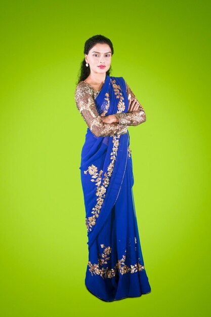 Photo full length of pretty indian woman standing in the studio while wearing a blue saree clothes and looking at the camera shot with green screen background