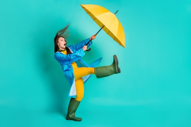 full length profile shocked lady stormy weather walk hold umbrella