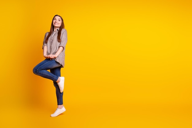 Full length profile side photo of young lovely woman good mood curious look empty space isolated over yellow color background