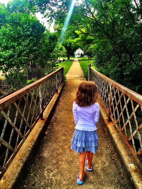 Full length rear view of girl walking on footbridge