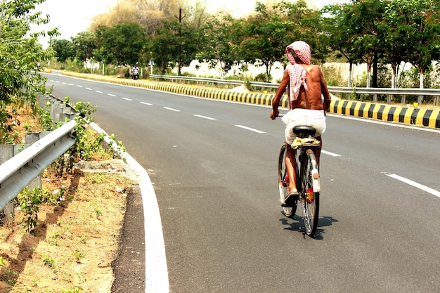Full length rear view of man riding bicycle on road