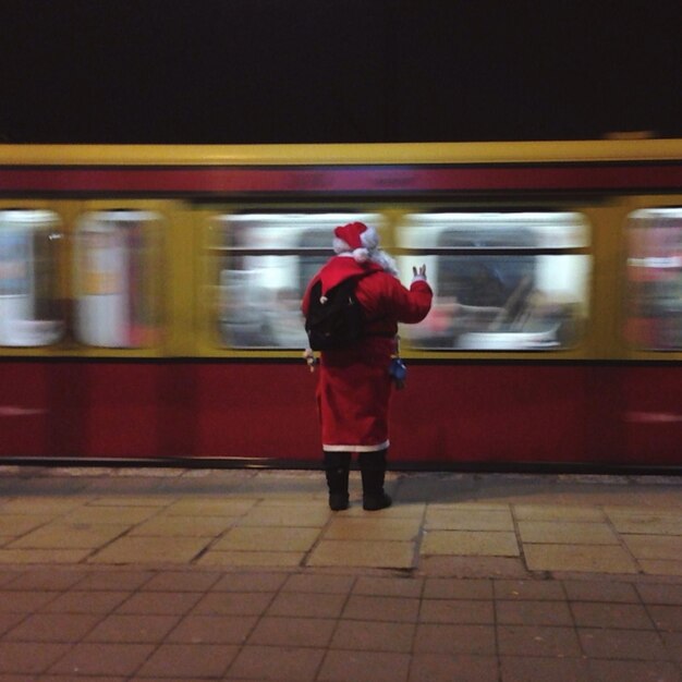 Photo full length rear view of man in santa costume on train platform