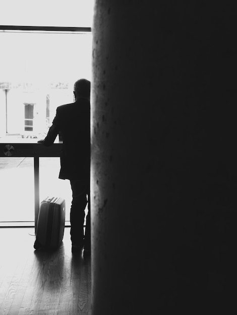 Photo full length rear view of man standing by suitcase