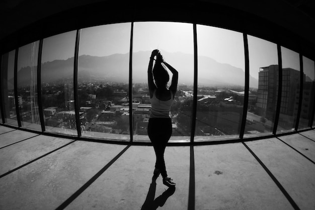 写真 街のガラスの窓のそばに立っている女性の全長後ろの景色