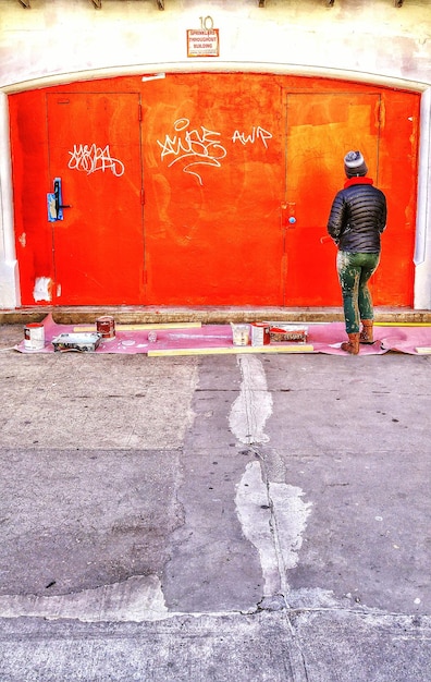 Photo full length rear view of person standing against red doors in building