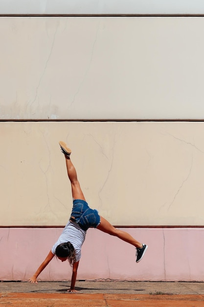 Full length rear view of woman practicing handstand against wall