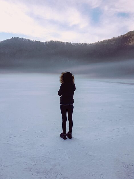 Full length rear view of woman standing on landscape against sky