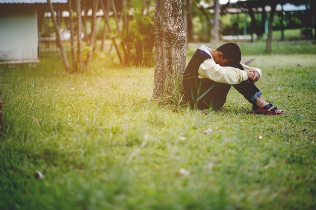 Foto lunghezza completa di ragazzo triste seduto sull'erba