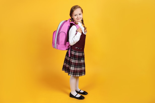 Full-length schoolgirl with a backpack behind her back.