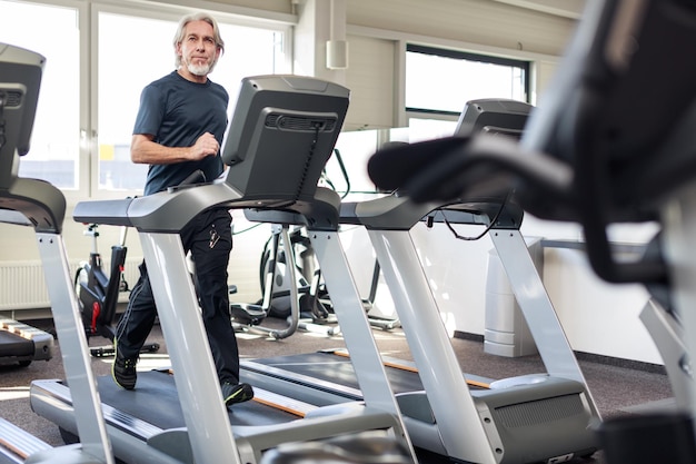 full length of senior man running on treadmill at gym