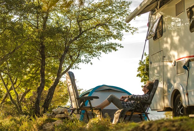 Full length of senior woman relaxing by camper trailer