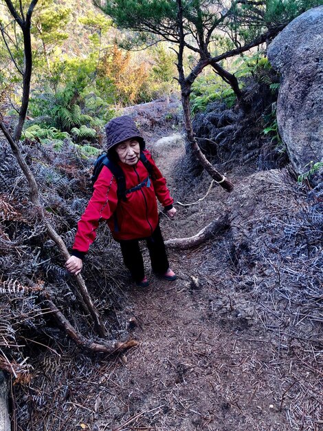 Foto lunghezza completa di una donna anziana in piedi nella foresta