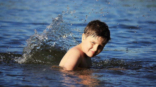 シャツのない男の子が水の中で微笑んでいる