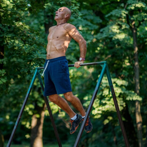 Photo full length of shirtless man exercising in park