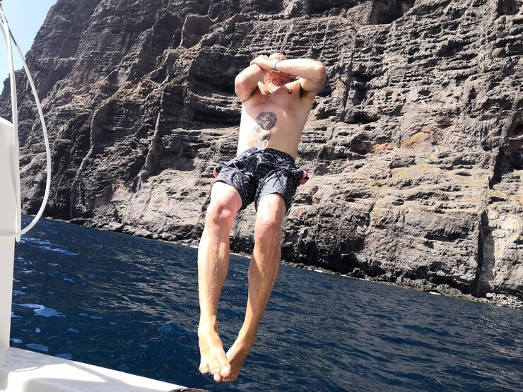Photo full length of shirtless man jumping in sea