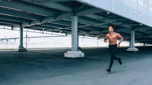 Foto lunghezza completa di un uomo senza camicia che corre in città