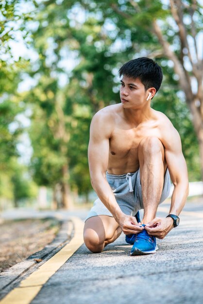 full length of shirtless man sitting on tree