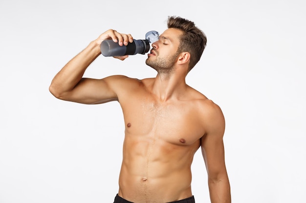 Full length of shirtless man standing against white background