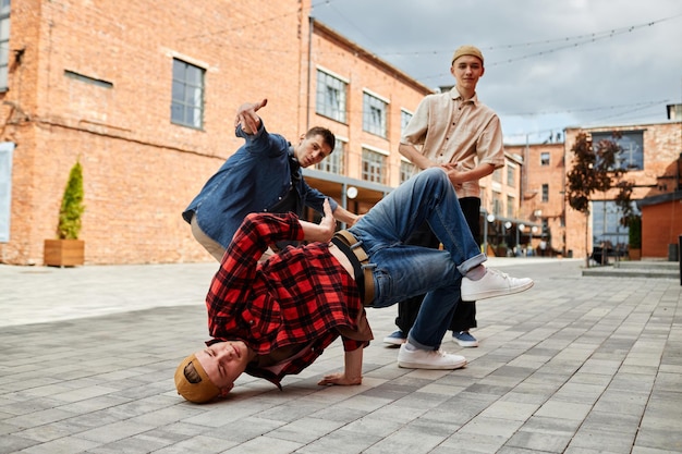 Full length shot of all male breakdance team posing outdoors in city setting