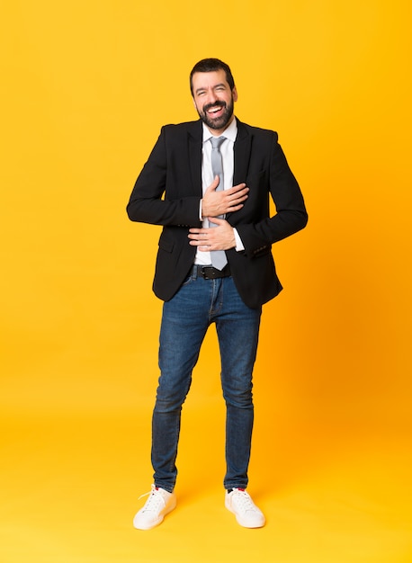 Full-length shot of business man over isolated yellow  smiling a lot