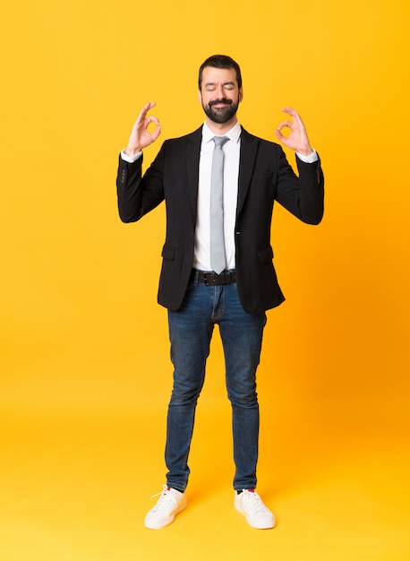 Full-length shot of business man over isolated yellow  in zen pose