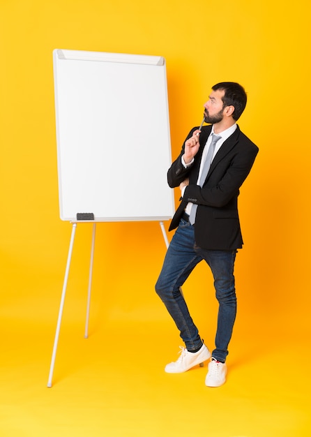 Full-length shot of businessman giving a presentation on white board over isolated yellow