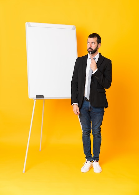 Full-length shot of businessman giving a presentation on white board over isolated yellow