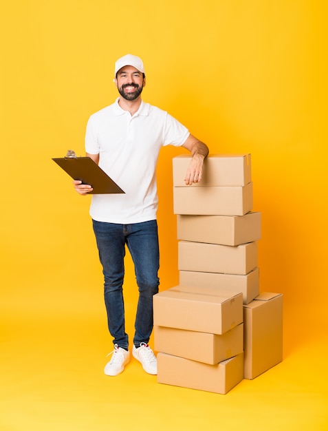 Full-length shot of delivery man among boxes over isolated yellow