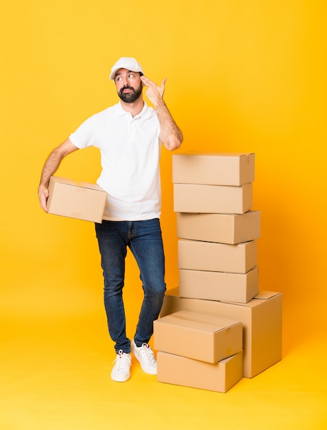 Full-length shot of delivery man among boxes over isolated yellow background 
