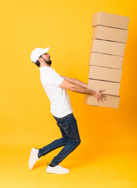 Full-length shot of delivery man among boxes over isolated yellow 