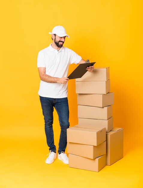 Full-length shot of delivery man among boxes over isolated yellow