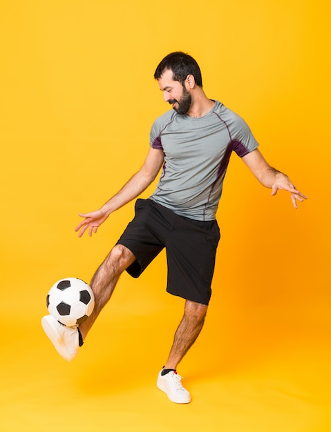 Full-length shot of a football player man over isolated yellow