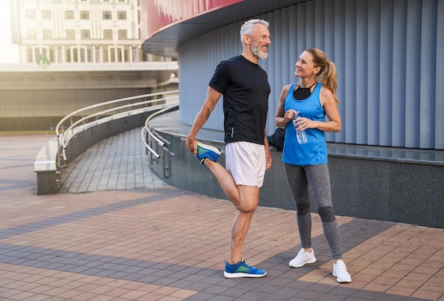 Full length shot of happy middle aged couple man and woman in sportswear smiling standing together