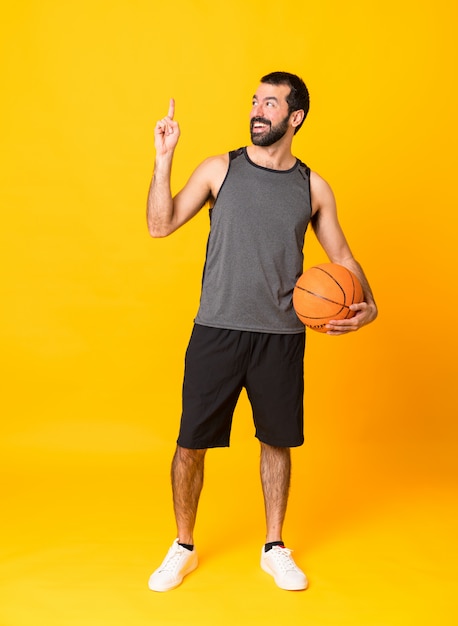 Full-length shot of man over isolated yellow playing basketball and having an idea