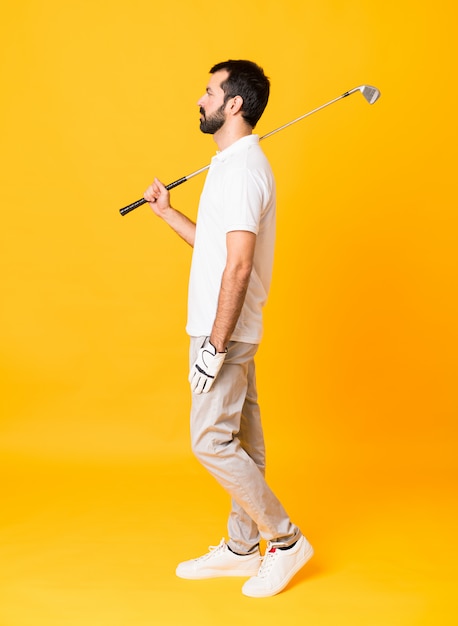 Full-length shot of man over isolated yellow  playing golf