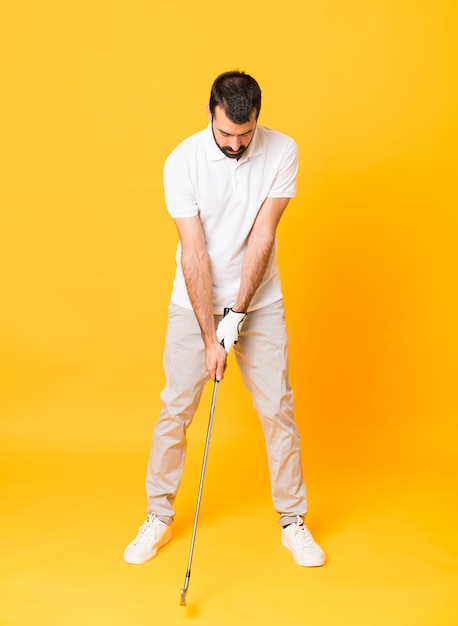 Full-length shot of a man playing golf over isolated yellow