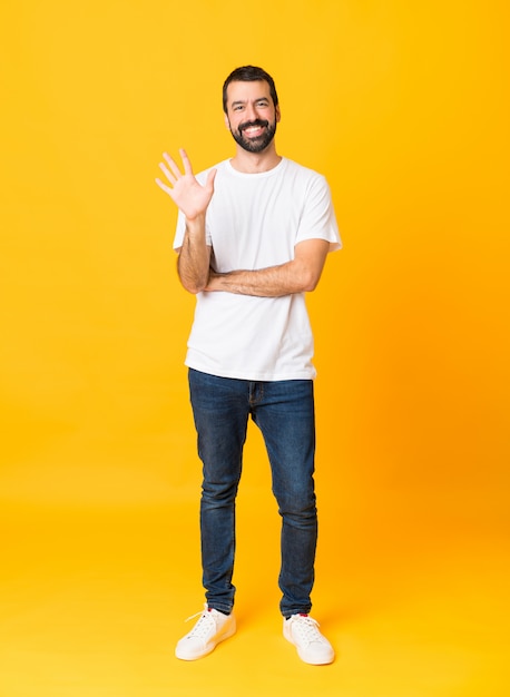 Full-length shot of man with beard over isolated yellow background counting five with fingers