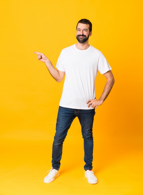 Full-length shot of man with beard over isolated yellow pointing finger to the side