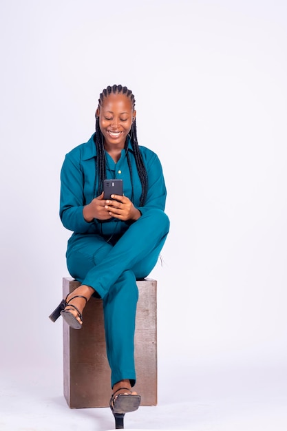 Full length shot of a pretty young woman sitting in an easy chair looking at her phone screen