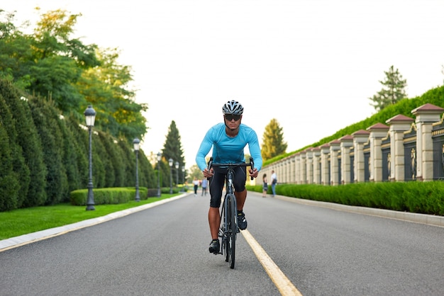 Полнометражный снимок профессионального велосипедиста-мужчины в спортивной одежде и тренировке защитного шлема в