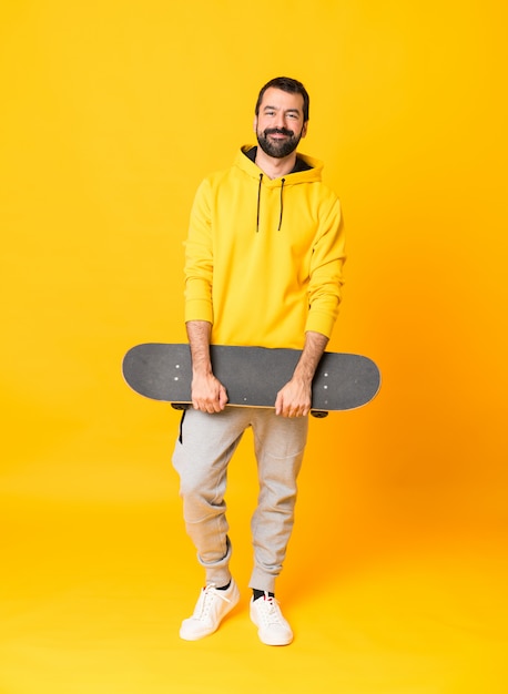 Full-length shot of a skater man over isolated yellow wall