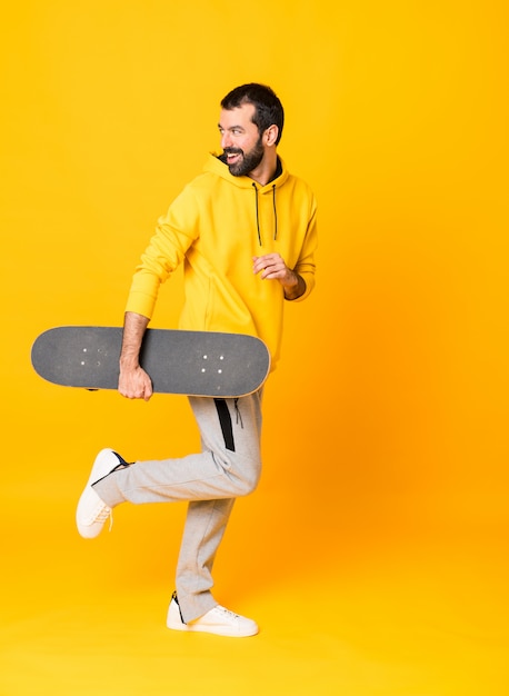 Full-length shot of a skater man over isolated yellow