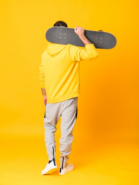 Full-length shot of a skater man over isolated yellow